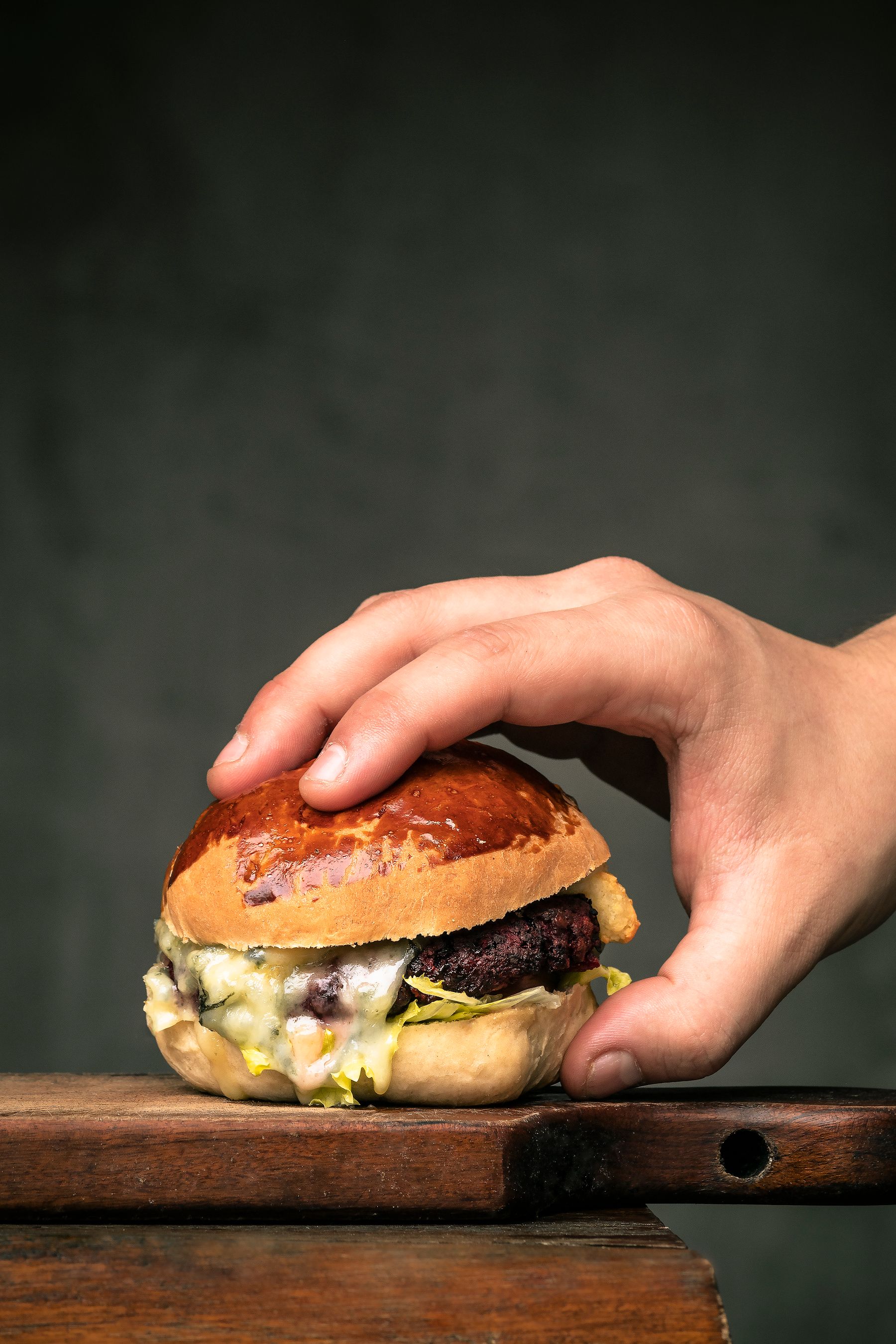 A hand picking up a stacked burger